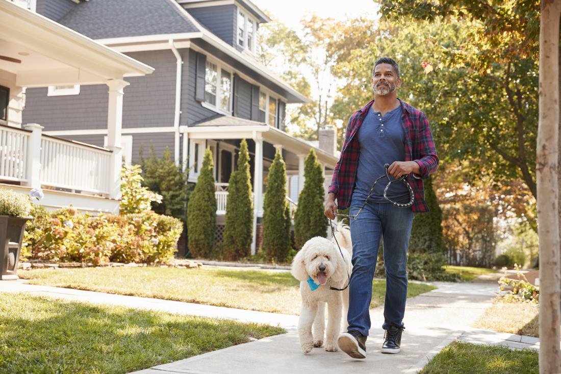 Man walking dog outside on street.